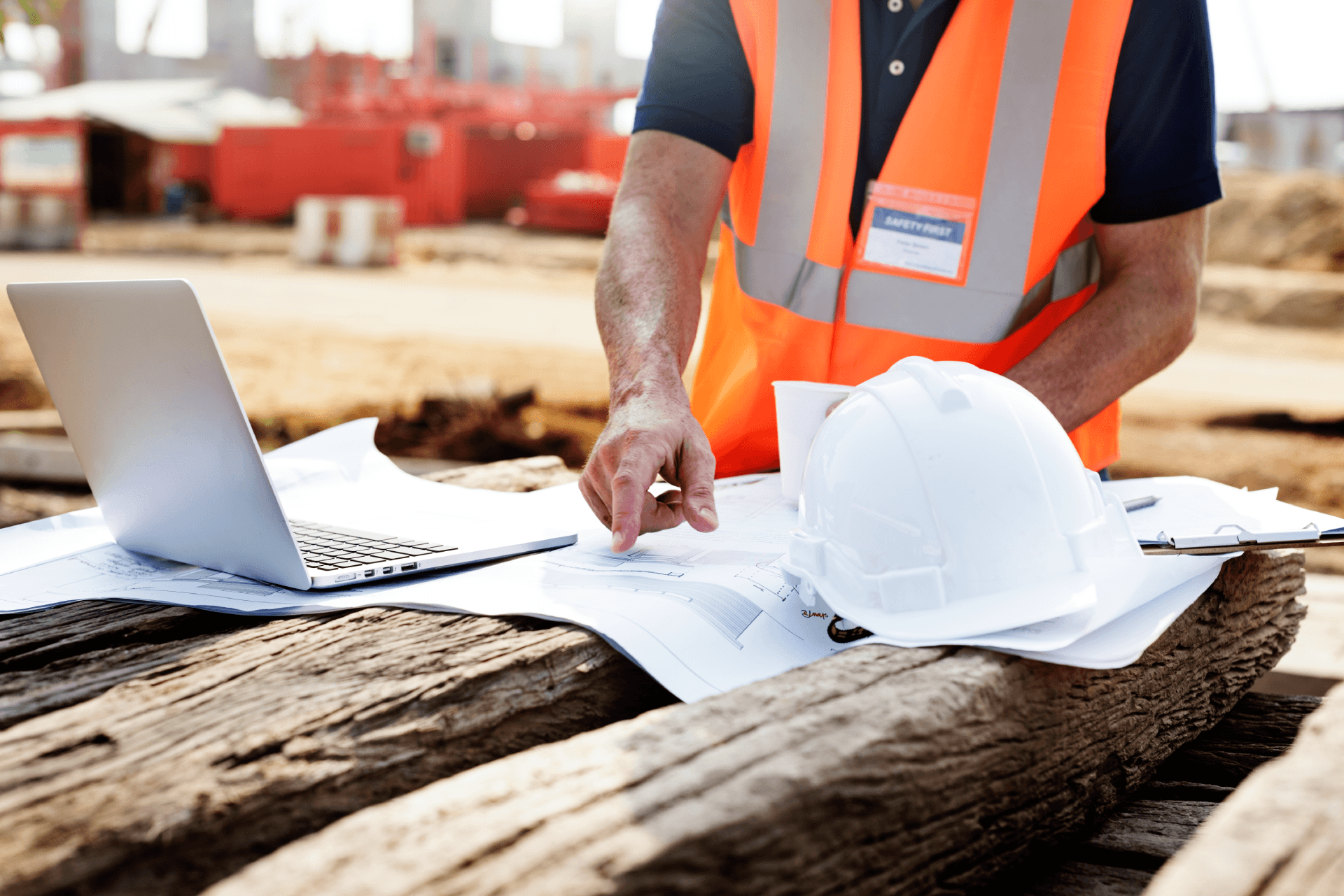 contractor on construction site using laptop and pointing at plans